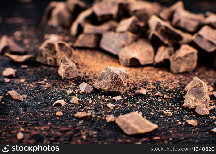 Pieces of dark chocolate on the table. On a rustic background. . Pieces of dark chocolate on the table.