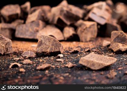 Pieces of dark chocolate on the table. On a rustic background. . Pieces of dark chocolate on the table.