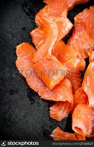 Pieces of delicious salted salmon. On a black background. High quality photo. Pieces of delicious salted salmon.