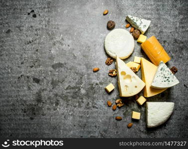 Pieces of different cheeses with walnuts. On the stone table.. Pieces of different cheeses with walnuts.