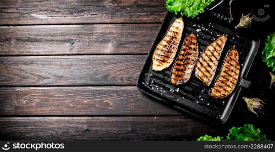 Pieces of eggplant grilled in a grill pan. On a wooden background. High quality photo. Pieces of eggplant grilled in a grill pan.