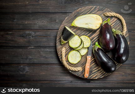 Pieces of eggplant on a cutting Board with a knife. On wooden background. Pieces of eggplant on a cutting Board with a knife.