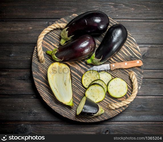 Pieces of eggplant on a cutting Board with a knife. On wooden background. Pieces of eggplant on a cutting Board with a knife.