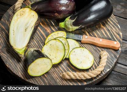 Pieces of eggplant on a cutting Board with a knife. On wooden background. Pieces of eggplant on a cutting Board with a knife.