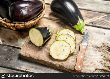 Pieces of eggplant on a cutting Board with a knife. On wooden background. Pieces of eggplant on a cutting Board with a knife.