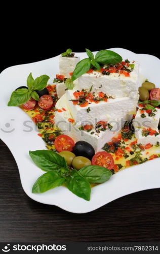 Pieces of feta with basil and olives, cherry tomatoes