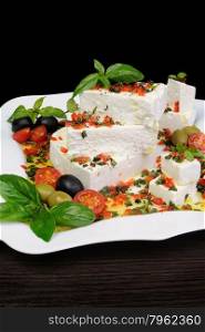 Pieces of feta with basil and olives, cherry tomatoes