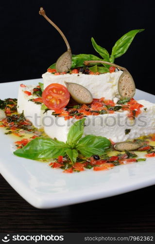 Pieces of feta with basil and olives, cherry tomatoes