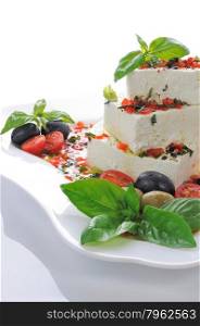 Pieces of feta with basil and olives, cherry tomatoes