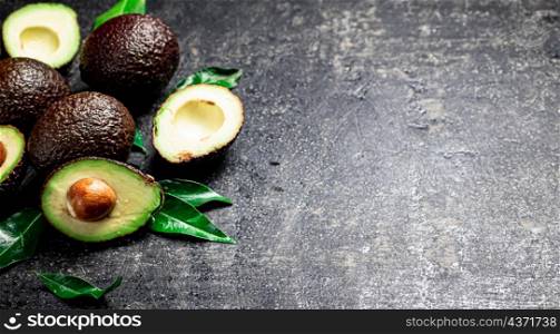 Pieces of fresh avocado with leaves. On a black background. High quality photo. Pieces of fresh avocado with leaves.