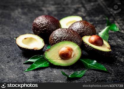 Pieces of fresh avocado with leaves. On a black background. High quality photo. Pieces of fresh avocado with leaves.