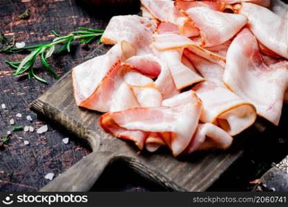 Pieces of fresh bacon on a cutting board with spices. Against a dark background. High quality photo. Pieces of fresh bacon on a cutting board with spices.
