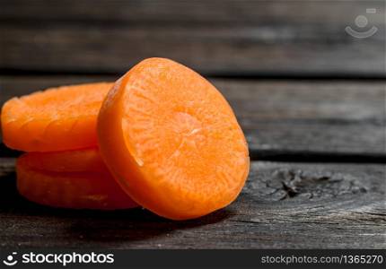 Pieces of fresh carrots. On black wooden background. Pieces of fresh carrots.