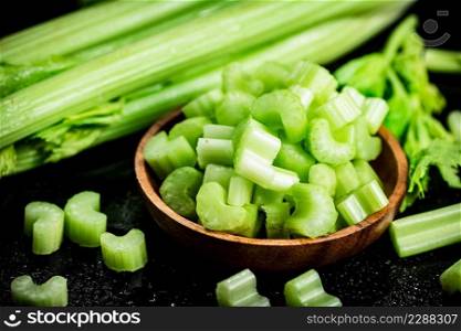Pieces of fresh celery in a wooden plate. On a black background. High quality photo. Pieces of fresh celery in a wooden plate. 