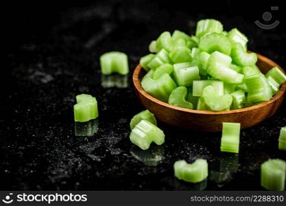 Pieces of fresh celery in a wooden plate. On a black background. High quality photo. Pieces of fresh celery in a wooden plate.