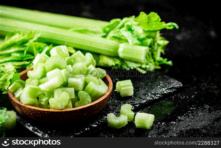 Pieces of fresh celery in a wooden plate. On a black background. High quality photo. Pieces of fresh celery in a wooden plate.