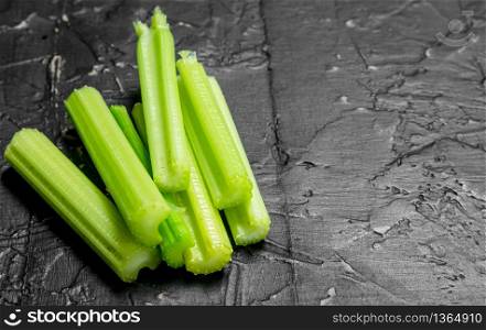 Pieces of fresh celery. On black rustic background. Pieces of fresh celery.