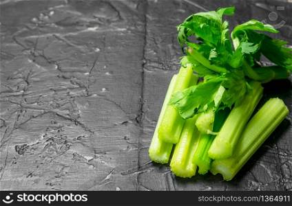 Pieces of fresh celery. On black rustic background. Pieces of fresh celery.