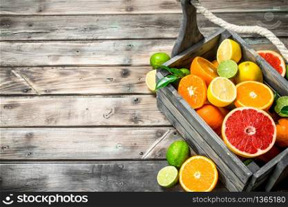 Pieces of fresh citrus in the box. On wooden background. Pieces of fresh citrus in the box.