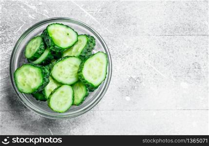Pieces of fresh cucumbers in a glass bowl. On rustic background. Pieces of fresh cucumbers in a glass bowl.