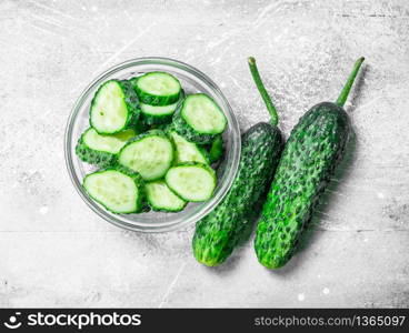 Pieces of fresh cucumbers in a glass bowl. On rustic background. Pieces of fresh cucumbers in a glass bowl.