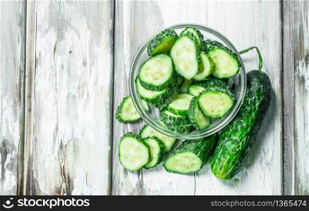 Pieces of fresh cucumbers in the bowl. On white wooden background. Pieces of fresh cucumbers in the bowl.