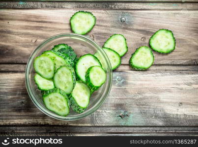 Pieces of fresh cucumbers in the bowl. On wooden background. Pieces of fresh cucumbers in the bowl.