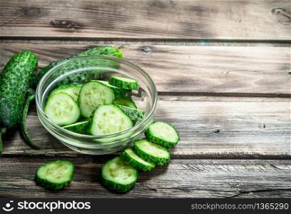 Pieces of fresh cucumbers in the bowl. On wooden background. Pieces of fresh cucumbers in the bowl.
