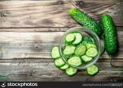 Pieces of fresh cucumbers in the bowl. On wooden background. Pieces of fresh cucumbers in the bowl.