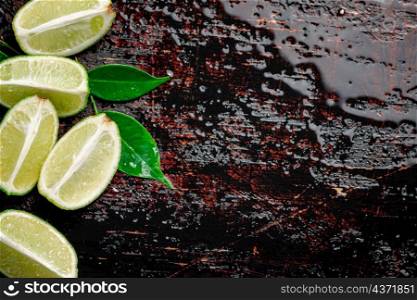 Pieces of fresh lime with foliage. Against a dark background. High quality photo. Pieces of fresh lime with foliage.