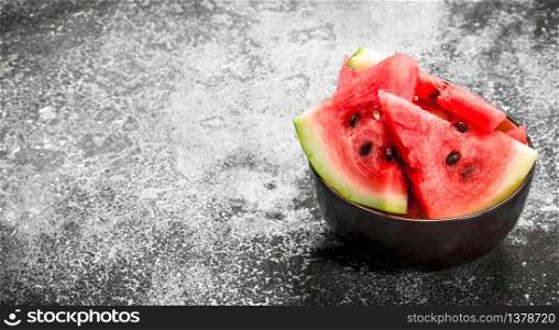 Pieces of fresh watermelon in a bowl. On a rustic background.. Pieces of fresh watermelon in a bowl.