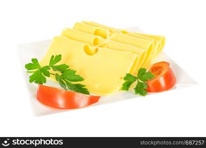 Pieces of fresh yellow cheese with parsley and tomatoes on a plate isolated on a white background in close-up.