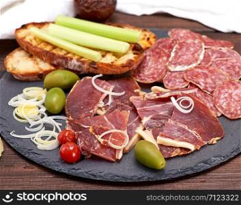 pieces of jamon and white fried bread for a sandwich on a black surface