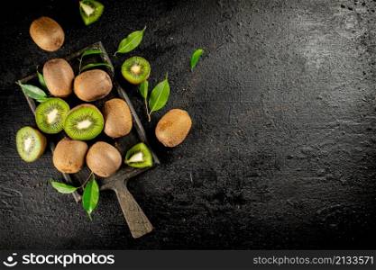 Pieces of kiwi with leaves on a cutting board. On a black background. High quality photo. Pieces of kiwi with leaves on a cutting board.