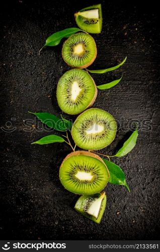 Pieces of kiwifruit with leaves. On a black background. High quality photo. Pieces of kiwifruit with leaves.