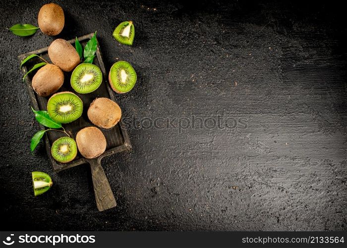 Pieces of kiwifruit with leaves. On a black background. High quality photo. Pieces of kiwifruit with leaves.
