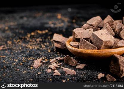 Pieces of milk chocolate on a plate. On a black background. High quality photo. Pieces of milk chocolate on a plate.