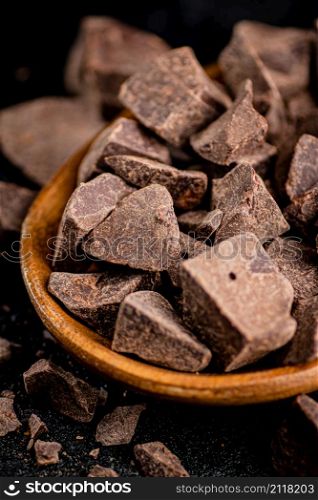 Pieces of milk chocolate on a plate. On a black background. High quality photo. Pieces of milk chocolate on a plate.