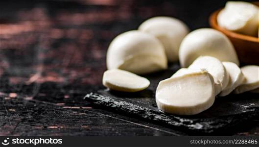 Pieces of mozzarella cheese on a stone board. Against a dark background. High quality photo. Pieces of mozzarella cheese on a stone board.