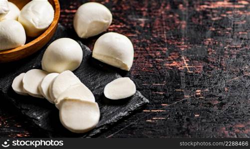 Pieces of mozzarella cheese on a stone board. Against a dark background. High quality photo. Pieces of mozzarella cheese on a stone board.