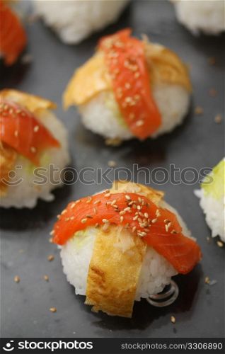 Pieces of nigirisushi: rice with a salmon or scrimp topping, decorated with sesame seeds