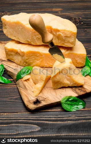 pieces of parmesan or parmigiano hard cheese and grapes on wooden cutting board. pieces of parmesan or parmigiano cheese and grapes