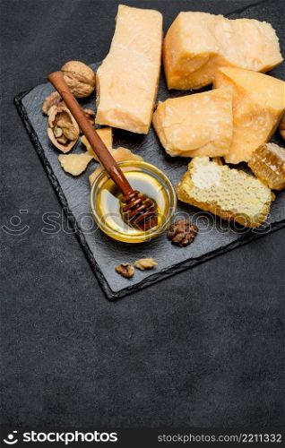 pieces of parmesan or parmigiano hard cheese and honey on dark concrete background. pieces of parmesan or parmigiano cheese and honey