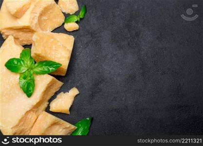 pieces of parmesan or parmigiano hard cheese on dark concrete background. pieces of parmesan or parmigiano cheese