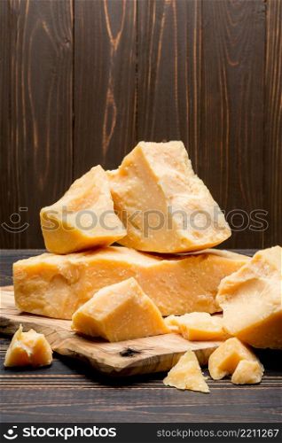 pieces of parmesan or parmigiano hard cheese on wooden cutting board. pieces of parmesan or parmigiano cheese