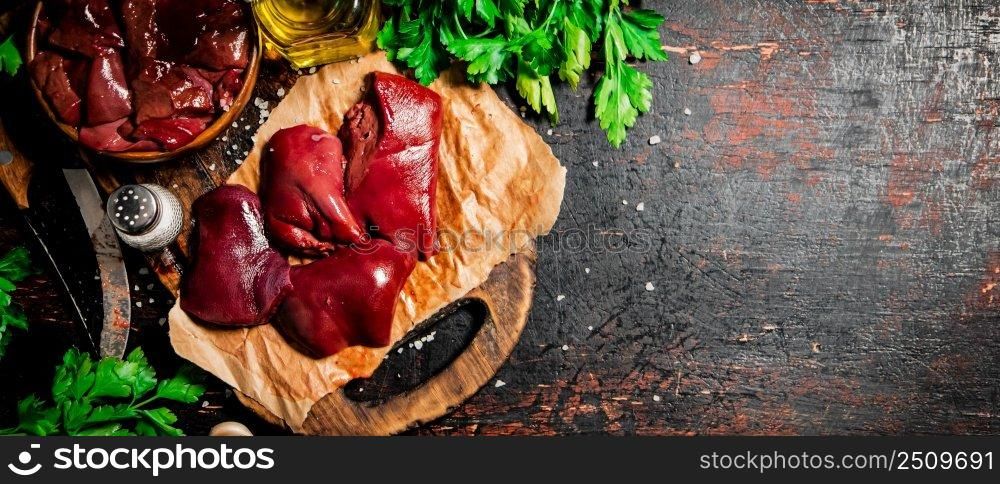 Pieces of raw liver with spices, oil and herbs. Against a dark background. High quality photo. Pieces of raw liver with spices, oil and herbs. 