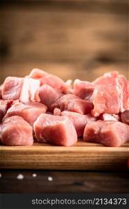 Pieces of raw pork on a cutting board. On a wooden background. High quality photo. Pieces of raw pork on a cutting board.