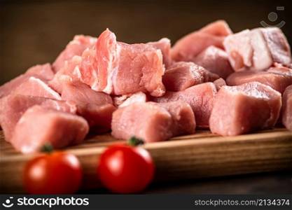 Pieces of raw pork on a cutting board. On a wooden background. High quality photo. Pieces of raw pork on a cutting board.