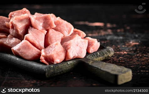 Pieces of raw pork on a cutting board on the table. On a rustic dark background. High quality photo. Pieces of raw pork on a cutting board on the table.