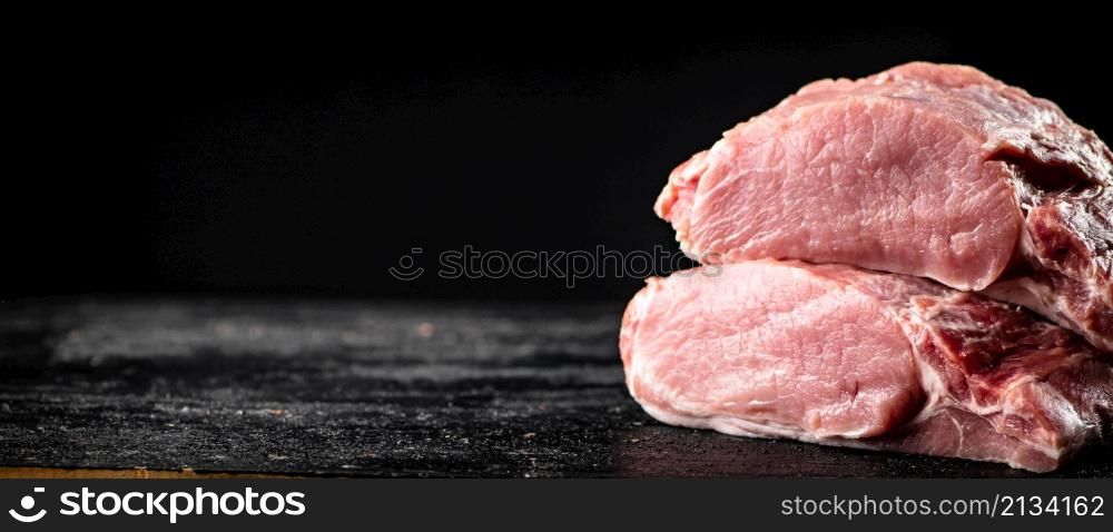 Pieces of raw pork on the table. On a black background. High quality photo. Pieces of raw pork on the table.